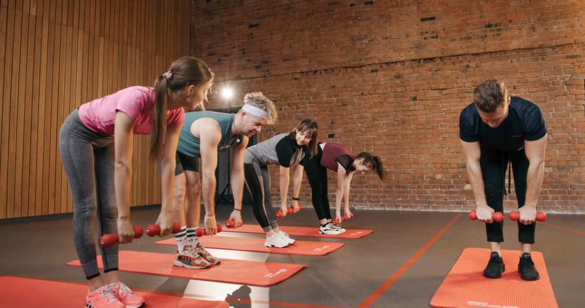 Fitness group performing exercises with dumbbells in a modern yoga studio setting.