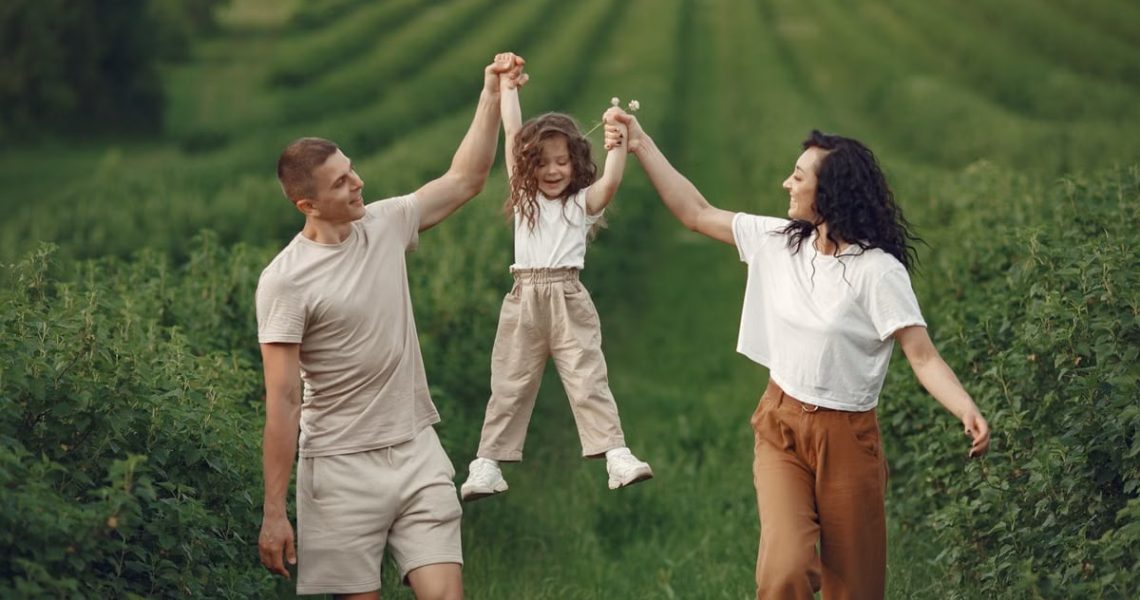 Joyful family moment in a green field during summer, capturing love and playfulness.